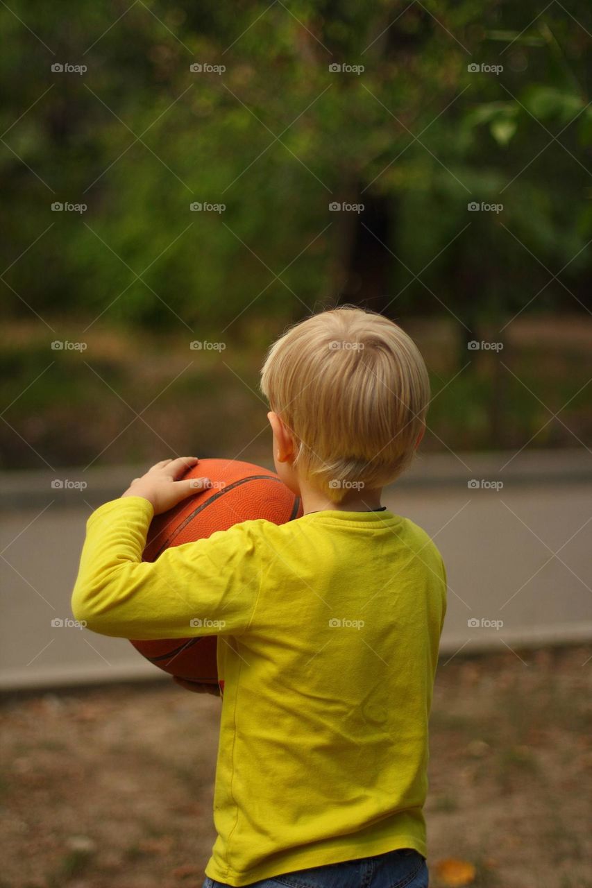Little boy playing basketball in the yard