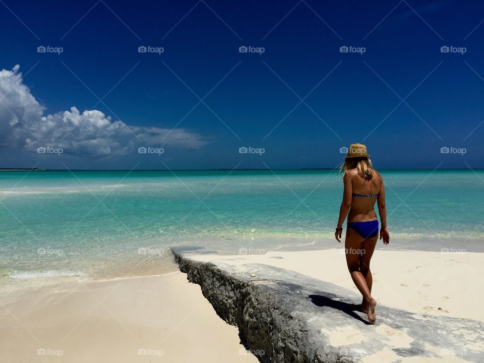 Rear view of woman walking on rock at beach