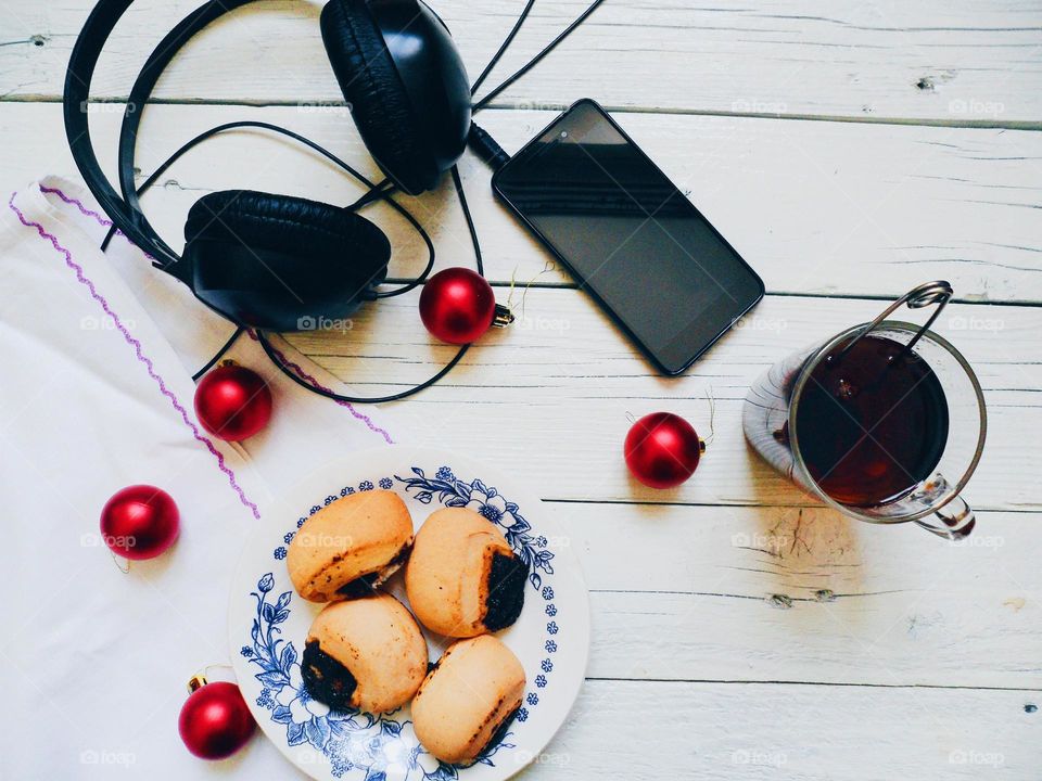 cup of tea, cakes, smart phone and headphones