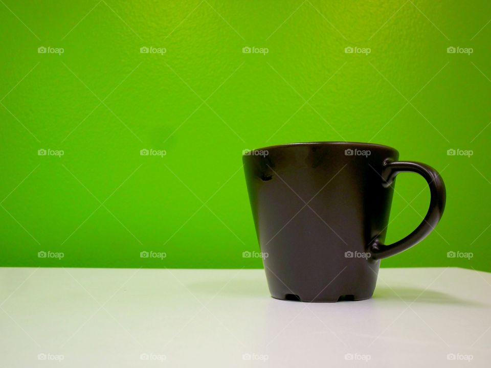 coffee mug on a table against a green wall