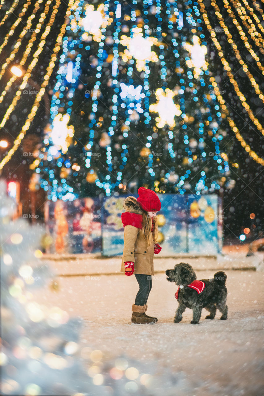 Cute little girl with her dog are playing new Christmas tree