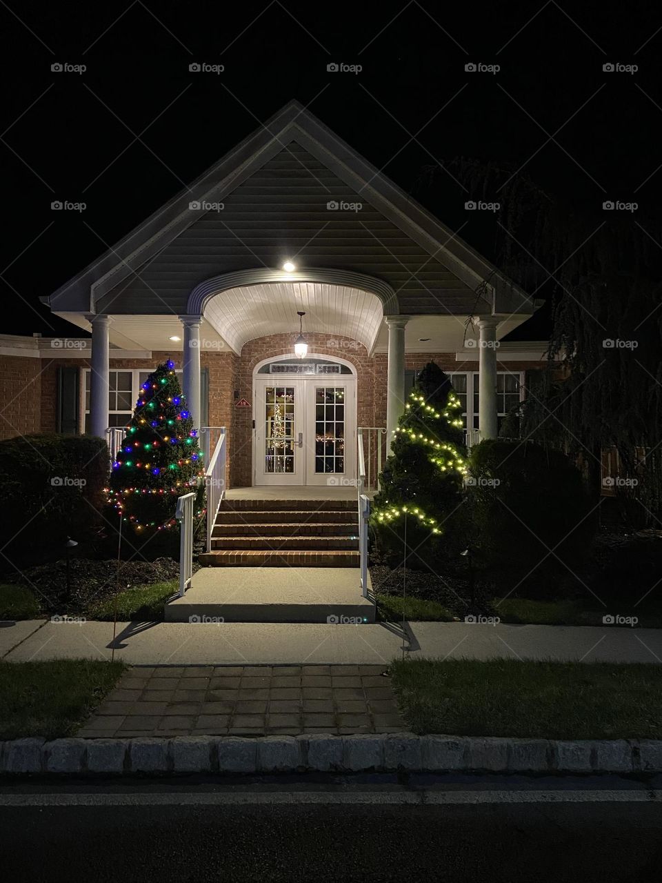 A community clubhouse building with trees lit up for Christmas outside and inside. 