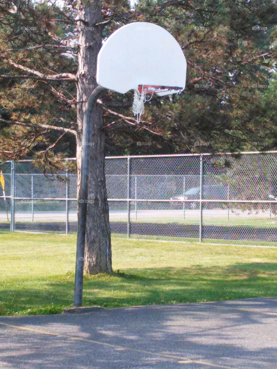 Basketball hoop, in poor shape. Basketball court, hoop is falling apart, seen better days