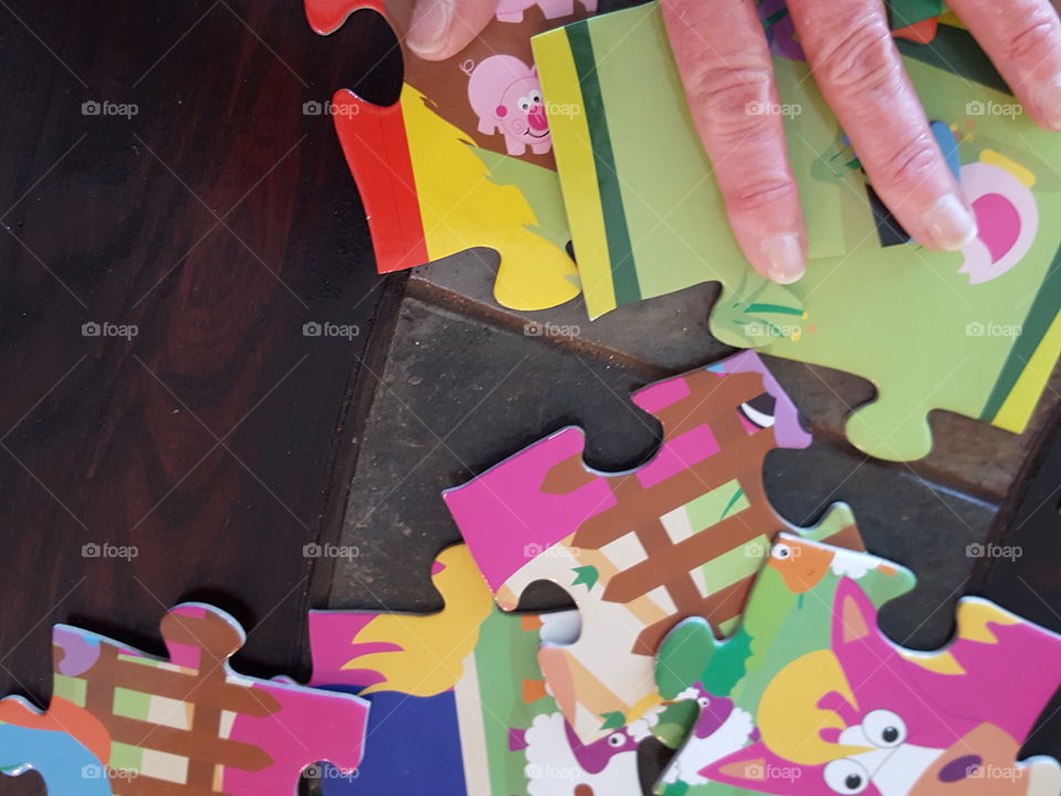 Jigsaw puzzle pieces with human finger