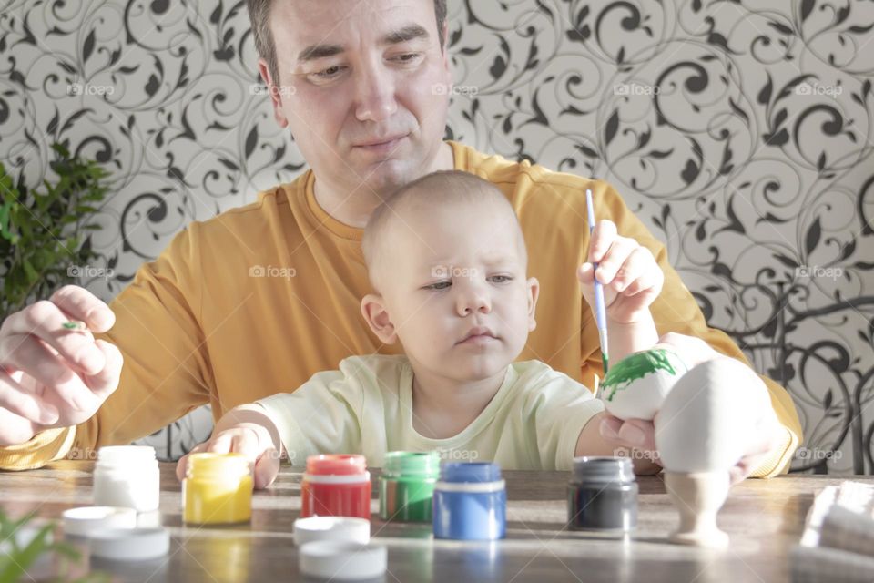 Dad teaches a small child to paint and have fun together.