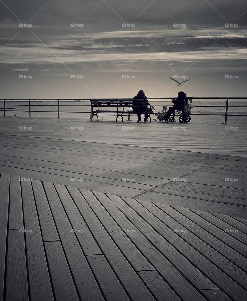Figures sitting on a boardwalk 