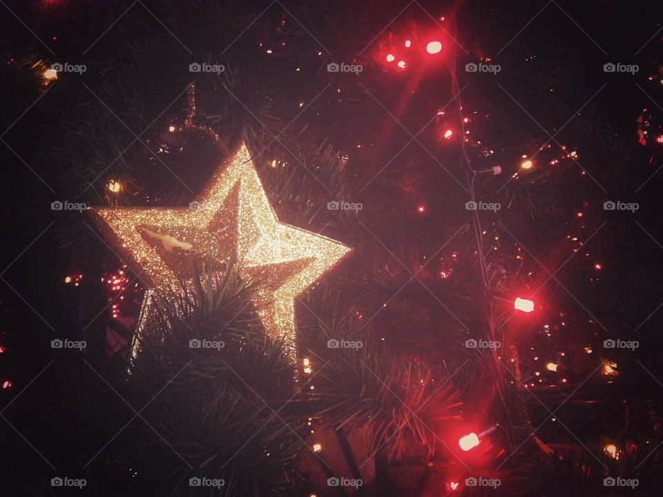 Gold plastic star, balls, red lights garland and other Christmas decorations on artificial fir tree in Moscow, Russia