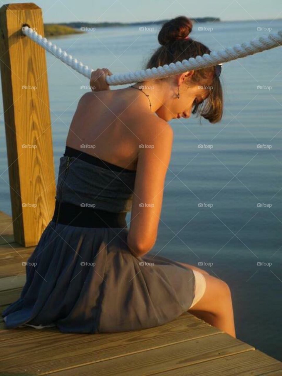 Young woman sitting on wooden pier