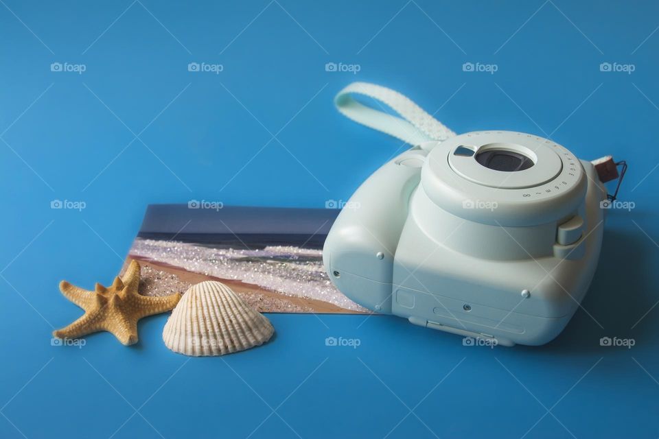 Seashell, postcard and camera on blue background. Concept of travel, vacation, sea 