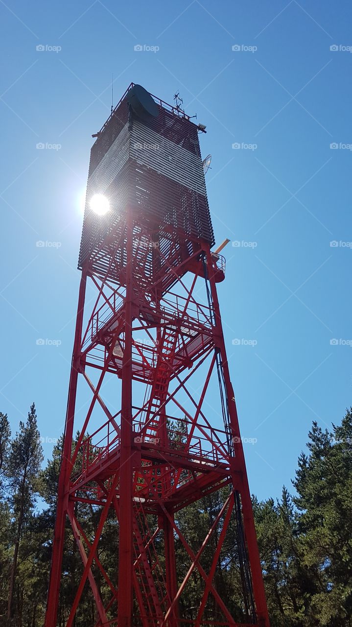 Lighthouse by the sun in a clear blue sky