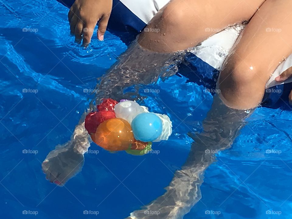 Legs in the pool. Legs in the swimming pool and playing with floating water balloons