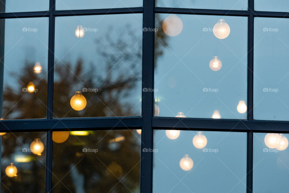 Christmas blurred decorative holiday lights through the window with city street reflection in glass and bokeh effect in background