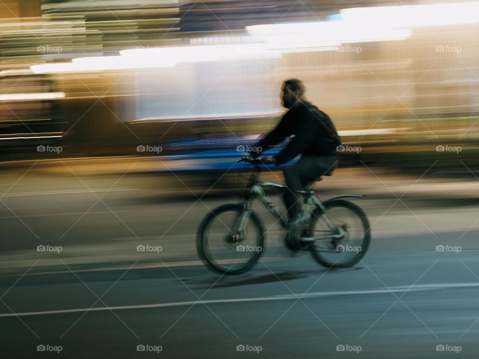 Men on a bicycle riding on night street, long exposure 