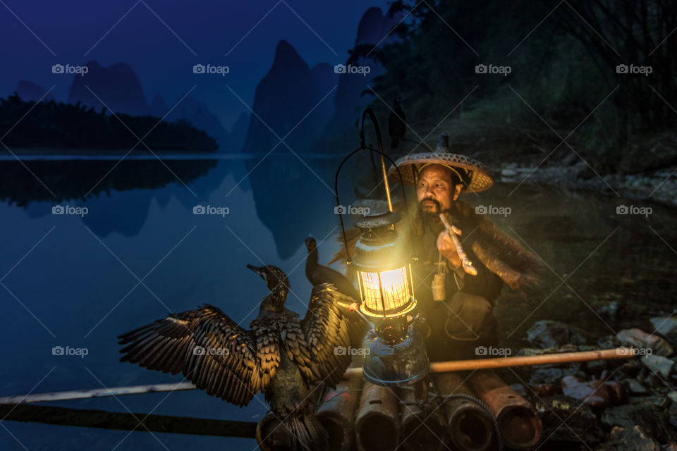 Cormorant fisherman and his birds with lantern on the river