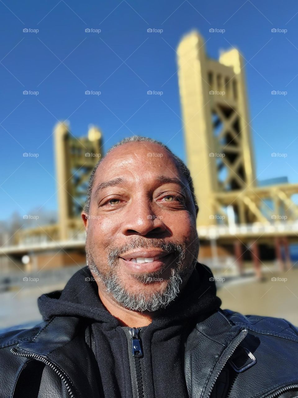 Self-portrait of a photographer standing along the river front with a golden bridge in the background