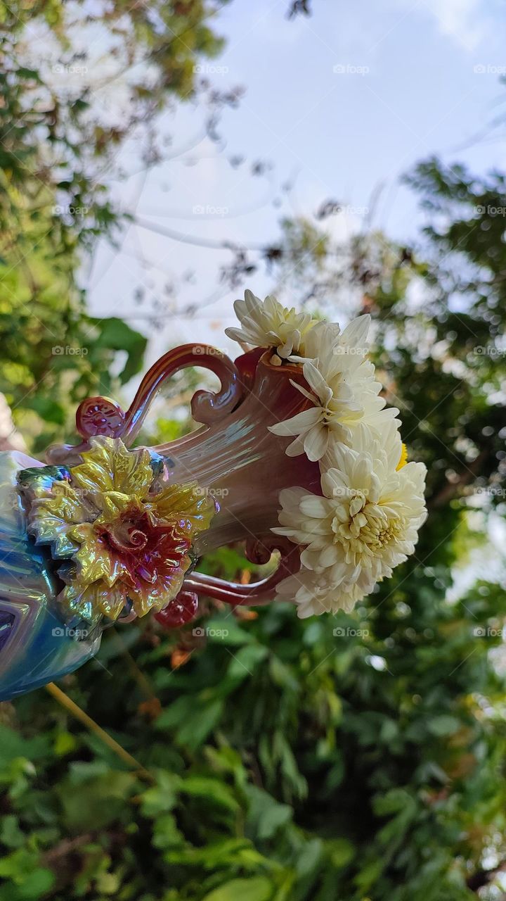 Beautiful white flowers in a colourful flowerpot with a flower sculpture, Flowers in a vase, colourful vase, white flowers in a vase