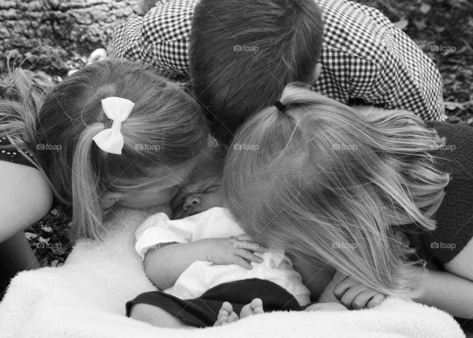 Sibling Love. Siblings kissing their new baby