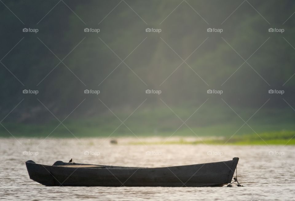 Barco ancorado no porto com a luz do sol deixando a imagem bastante suave .