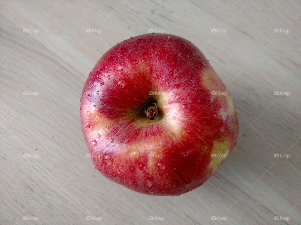 Top down of a red apple on a wooden surface.