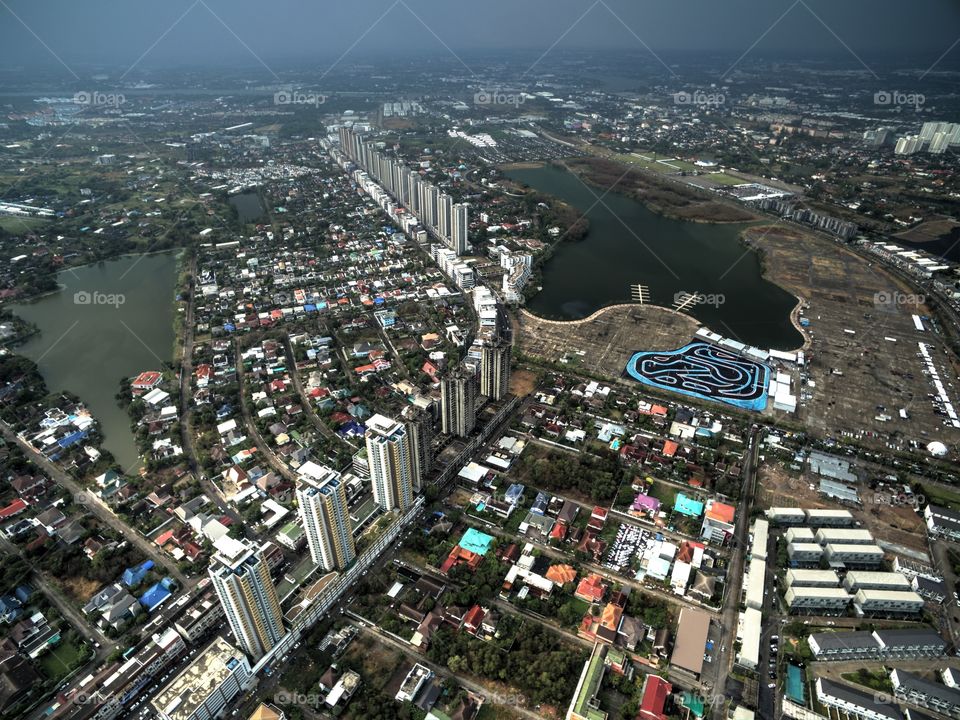 vertical panorama of the city, Bangkok taken with drone, high angle view showing tennis court, speed park and buildings condominium