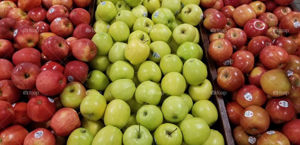 A lot of green Granny Smith apples and red Gala apples sitting separately in a Kroger grocery store.