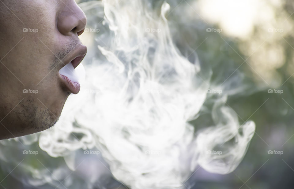 Smoke out of the mouth of a man.