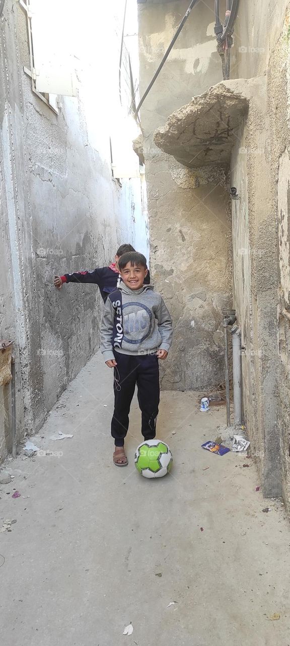Children playing football in a narrow and simple alley, but they feel joy