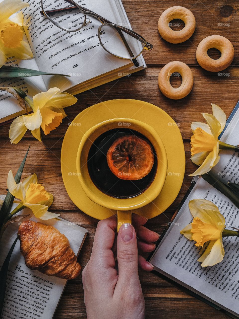 Breakfast flat lay with coffe, croissant, books and yellow flowers