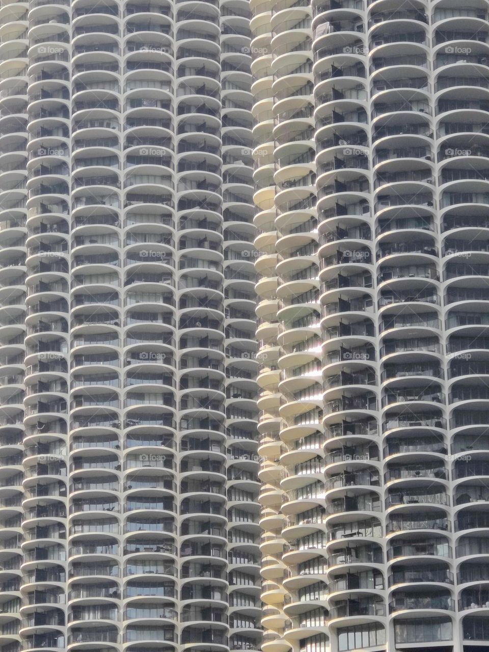 A very tall condo building with lots of repeating outdoor balconies in the city centre of Chicago.