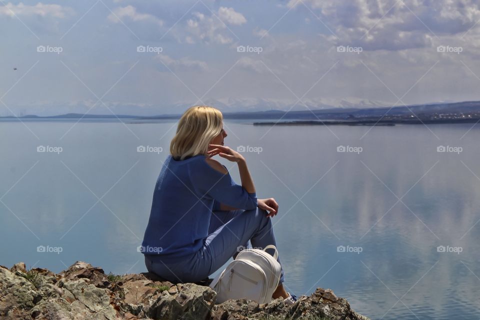 Blonde girl sitting by the lake