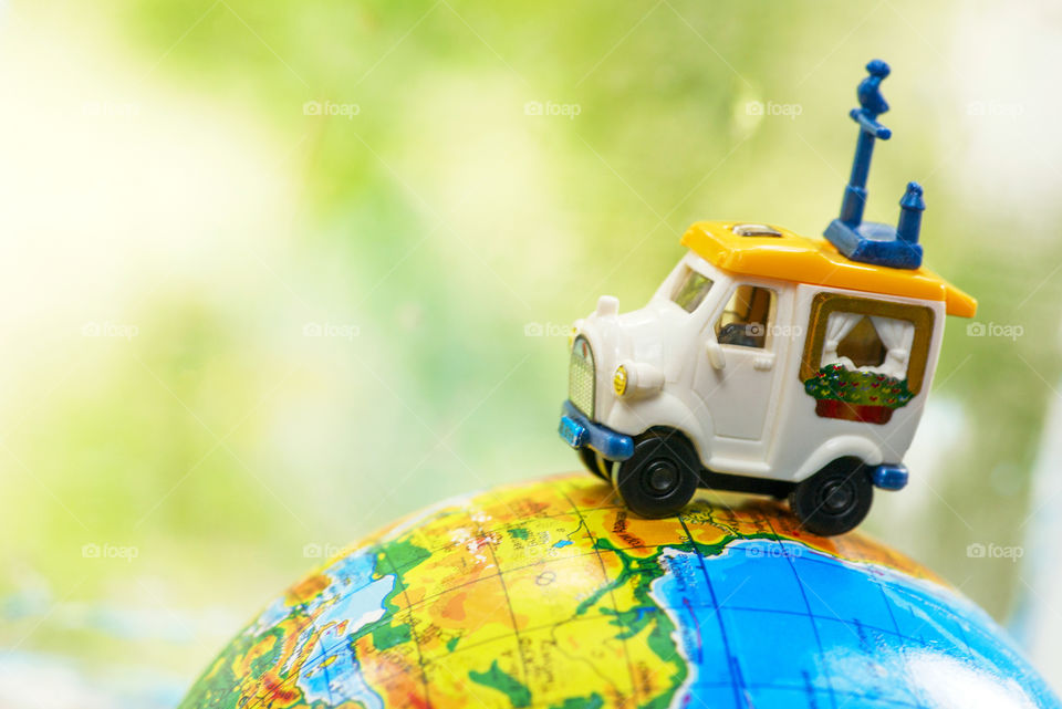 A car on globe on green background. Miniature car toy on globe