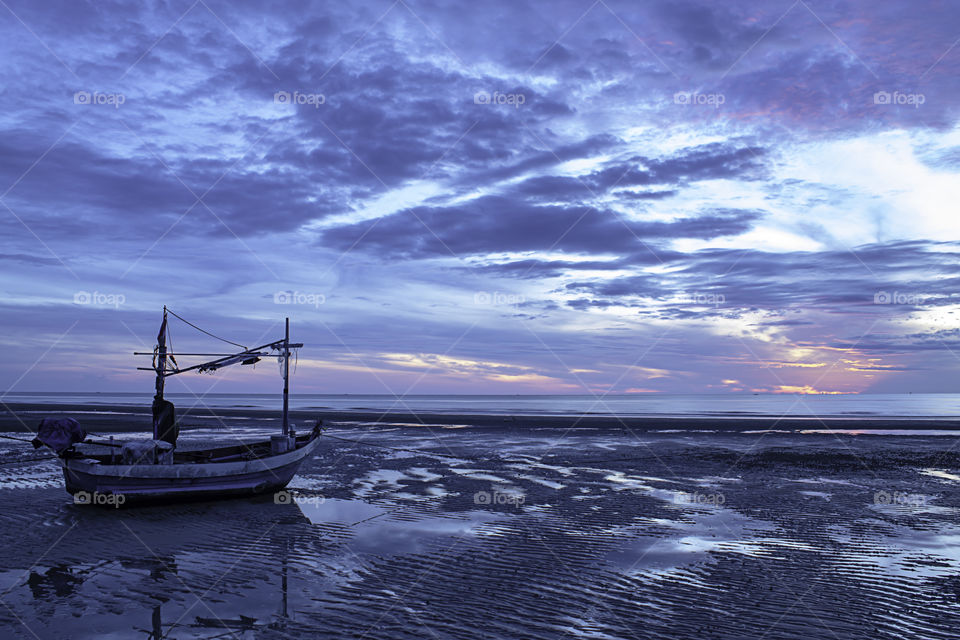 The morning sun light in the sea and the boat on the beach.