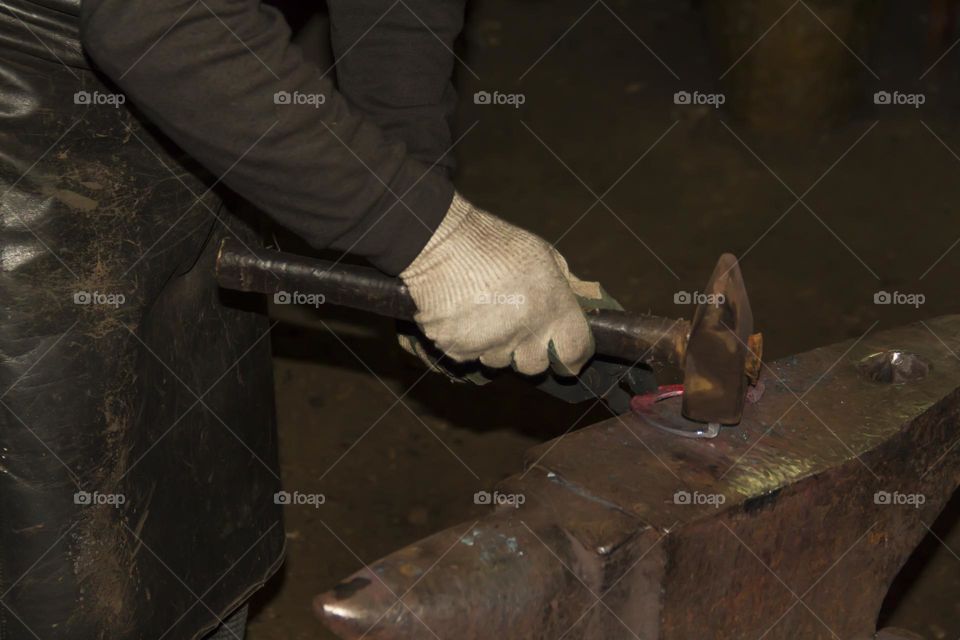 A blacksmith on an anvil makes a horseshoe and metal products from red-hot material.  Blacksmith workshop