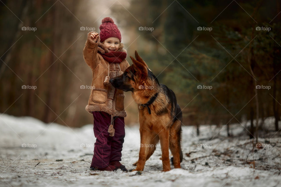 Little girl with German shepherd 6-th months puppy at early spring forest