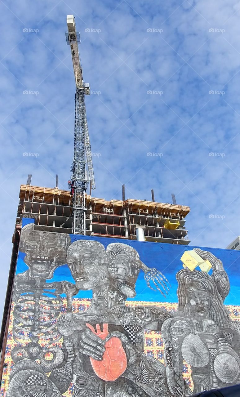 Zio Ziegler Mural on Webster Street Oakland California with background view of sky and apartment building construction site.