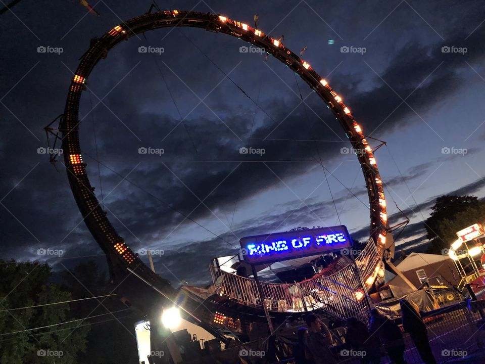 Ring of Fire ride at a carnival late at night with pretty, dark clouds stretching across the sky.