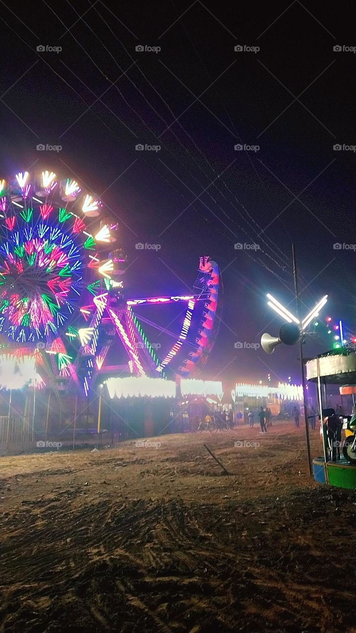 "Vibrant and lively scene from the local mela, filled with colorful stalls, excited crowds, and traditional festivities. The air is filled with laughter and the aroma of street food, creating a joyous atmosphere. #Mela #FestivalVibes #StreetFood