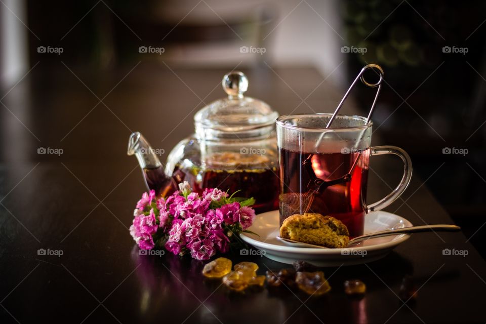 Cup of tea and tea pot with rock sugar on wooden table in a café