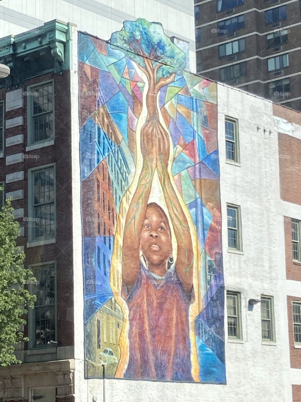 A mural on a city wall of a child holding a tree by its roots