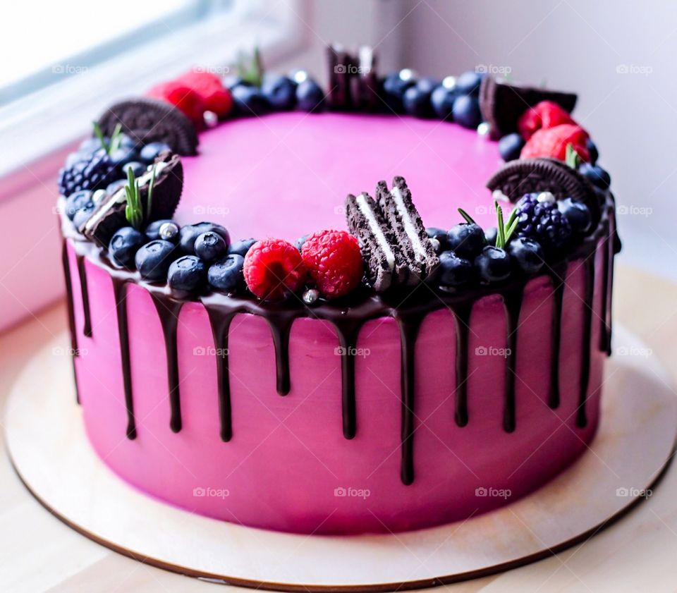 Tasty cake with dark chocolate glossy glaze and garnished with blackberry and raspberry.