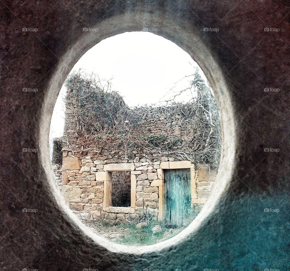 Ruine d'une maison en vieille pierres vu depuis un trou