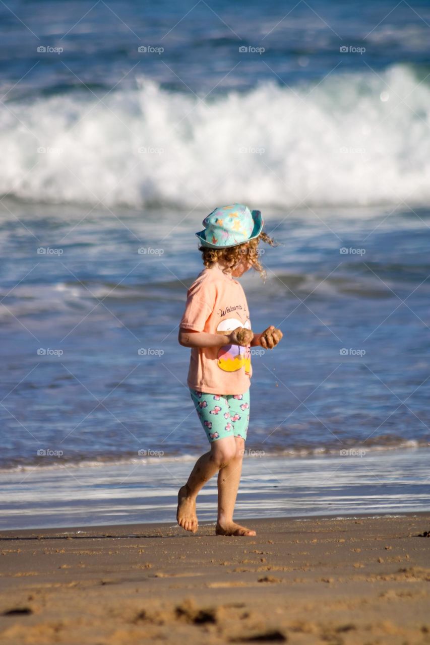 Little girl at the beach with sand in her hands