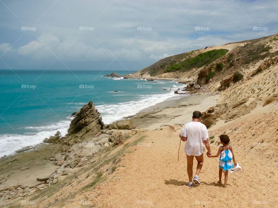 Father and daughter walking on a Brazilian beach