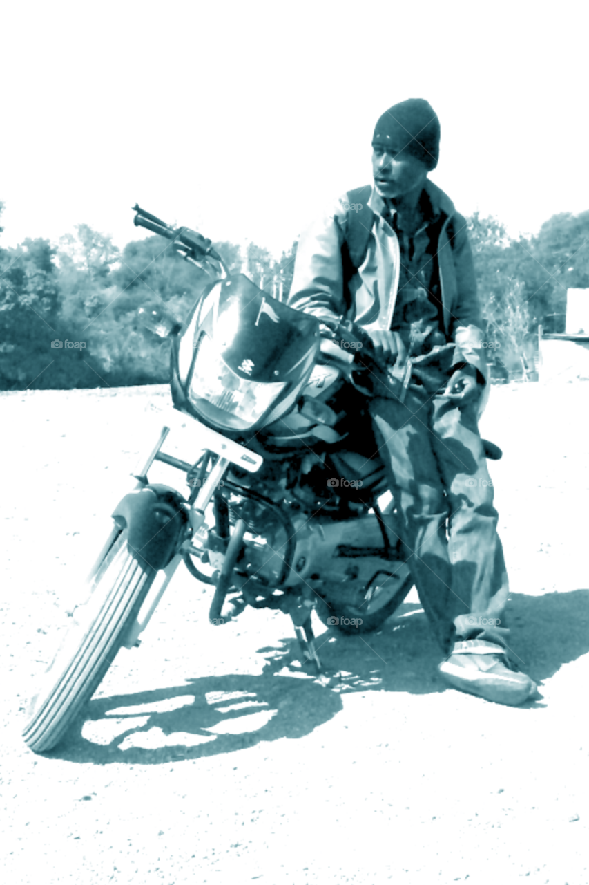 Photo of a man/photo of a man with a motor bike/photo of a man wearing a jacket/photo of a black and white man/black white photo of a model/model of a model/full photo of a model/photo of a male model/photo of an Indian model Standing