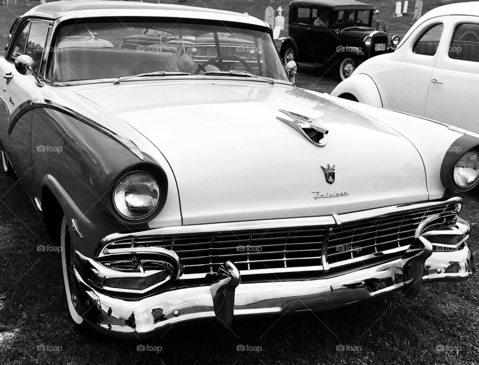 Black and white image of classic antique cars. Ford Fairlane , model t in background. 