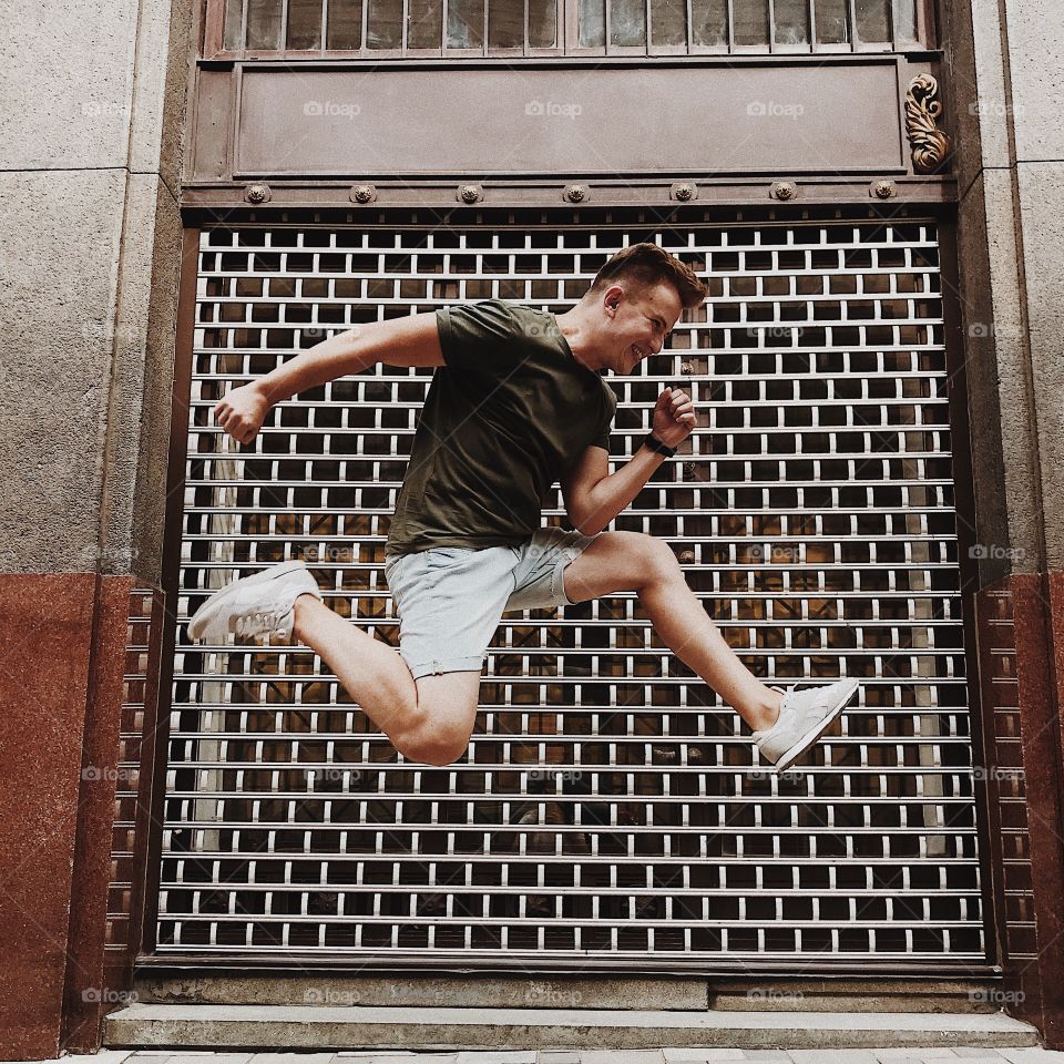 Young man jumping in street. Beautiful background.