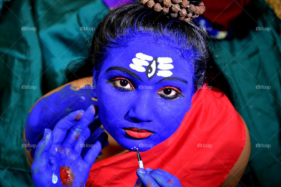 A girl is being painted as God Shiva during the festival of Shivratri