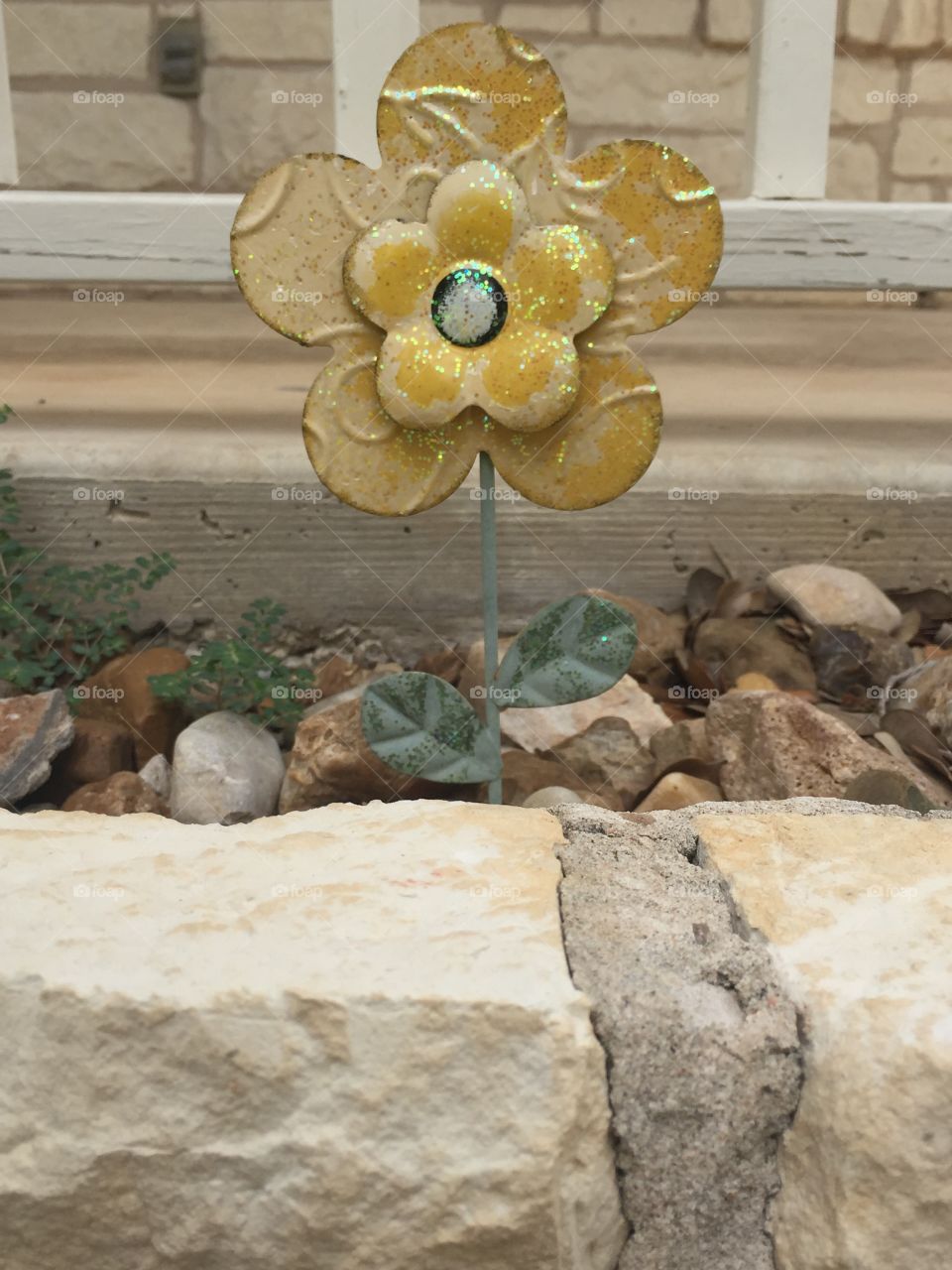 Yellow metal flower art in a rock bed for landscaping 