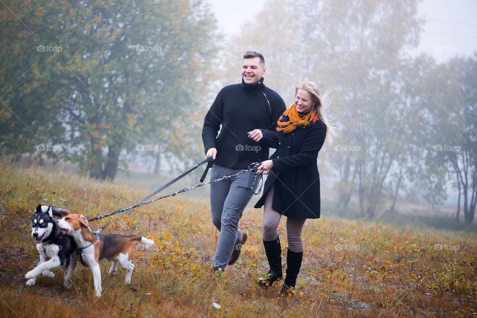 Happy family run with two dogs in autumn park