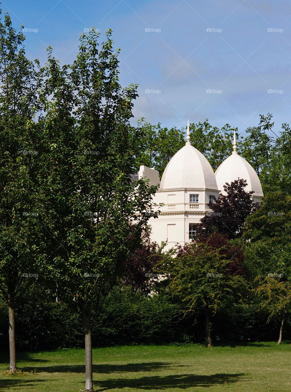 A beautiful building with multiple domes in the trees viewed from a park on a sunny summer day. 